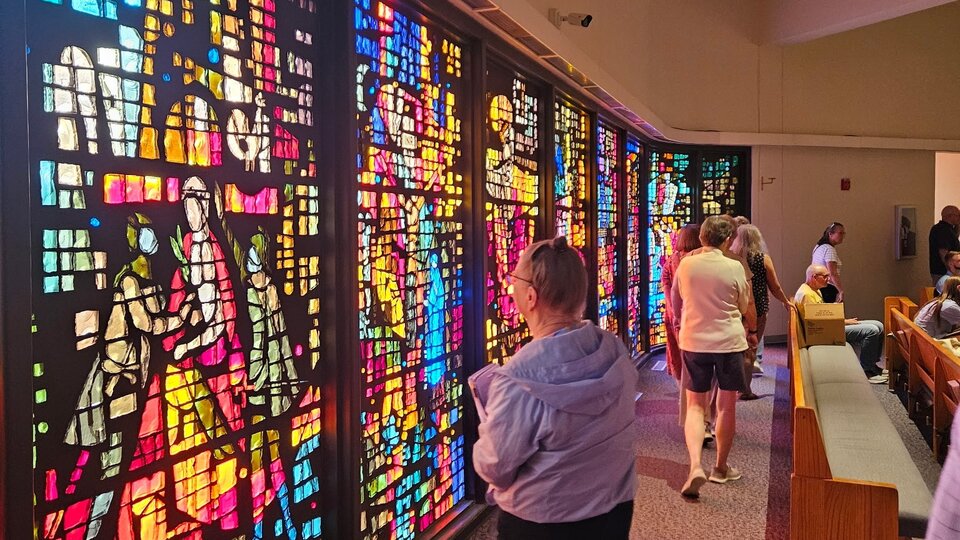 Stained glass windows in a church, vibrant colors illuminating visitors.